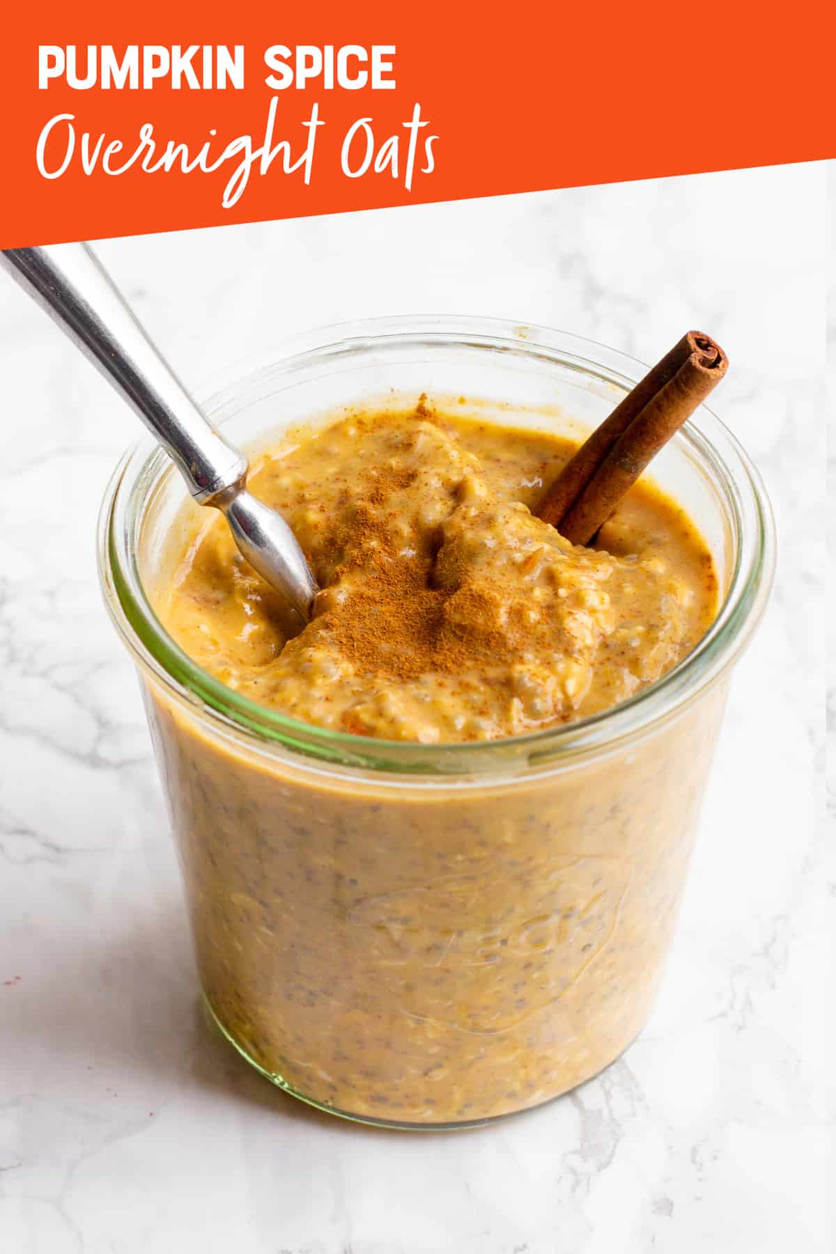 A clear glass jar filled with Pumpkin Spice Overnight Oats, with a spoon sticking out. A text overlay reads "Pumpkin Spice Overnight Oats."