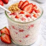 A jar of strawberry cheesecake overnight oats sits on a marble countertop