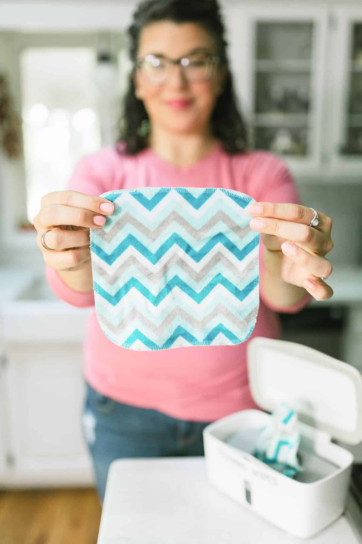 Woman in a pink shirt holding out a square flannel wipe to use as a cleaning wipe