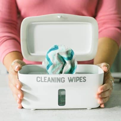 Woman's hands holding a wipes dispenser full of DIY Disinfecting Wipes.