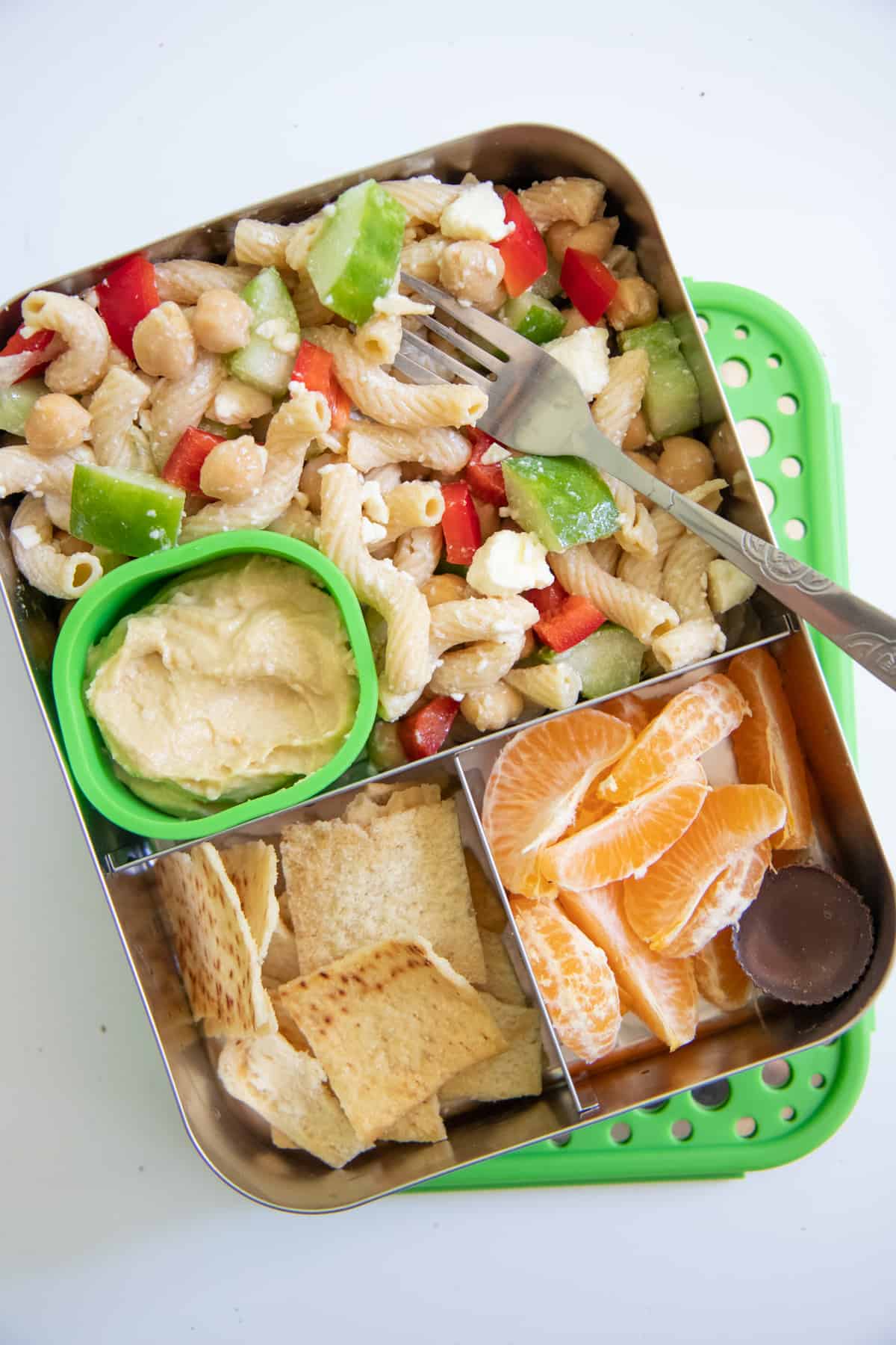 School Lunch Ideas: Stainless steel lunch box with Greek pasta salad, pita chips and hummus, and clementine slices.