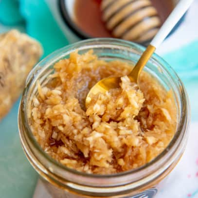 A horseradish and honey natural sinus relief home remedy in a glass jar, with a spoon dipping in to it.
