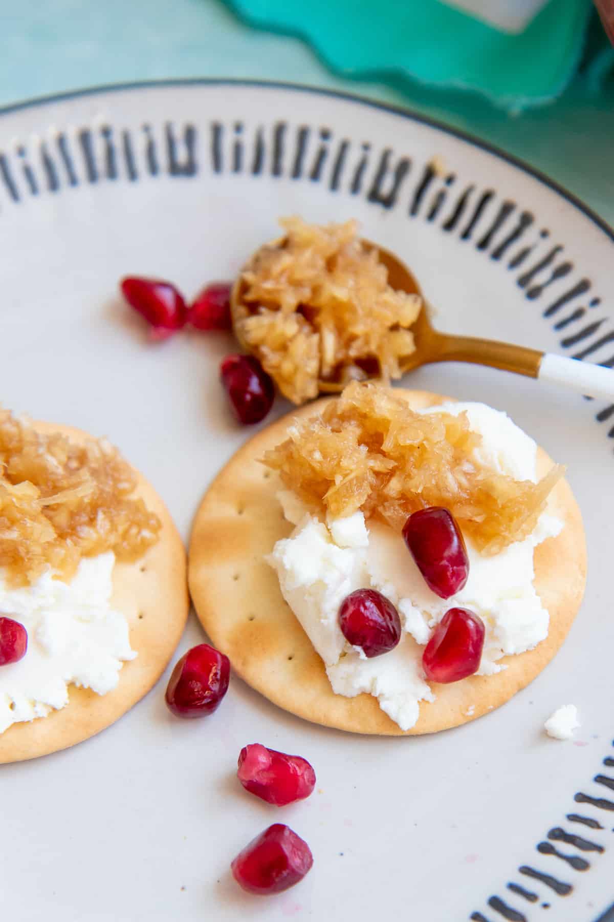 Thin wafer crackers spread with goat cheese and garnished with pomegranate arils and a horseradish honey condiment.