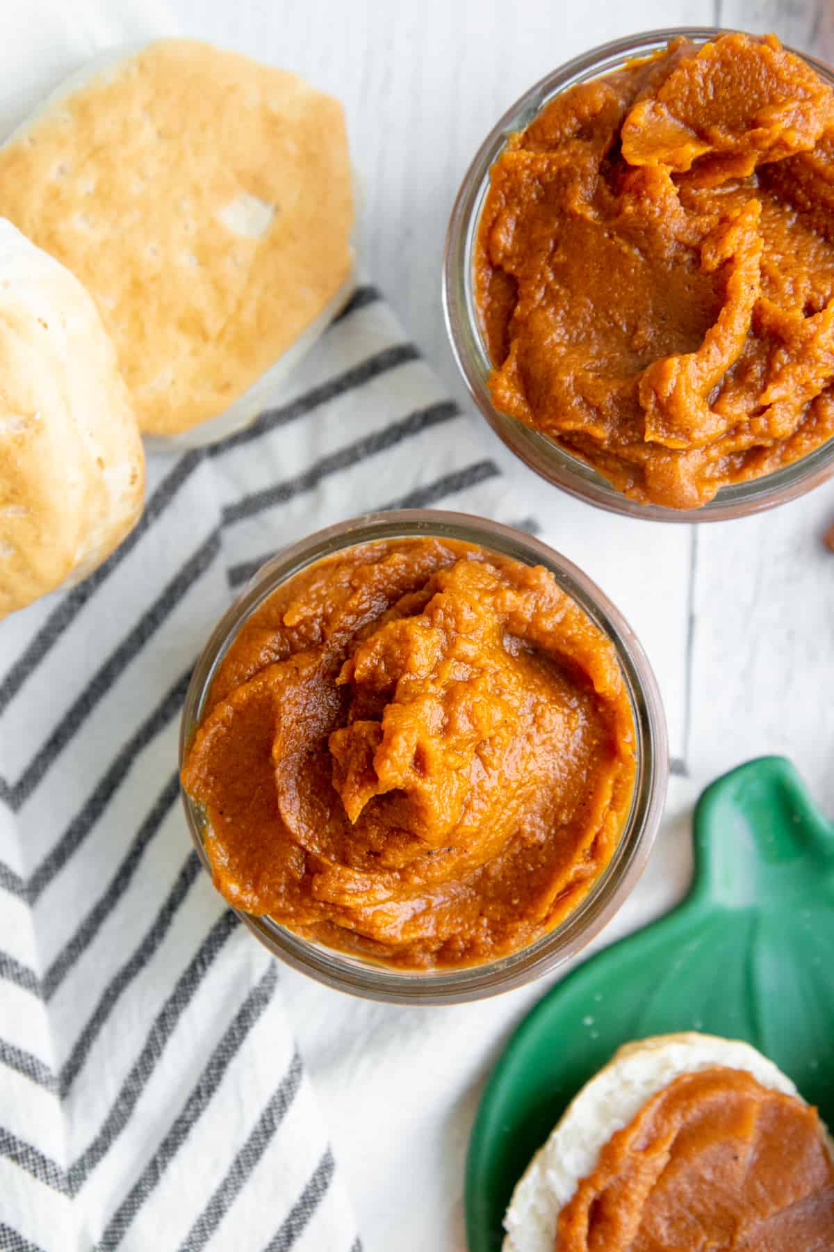 Overhead view of Slow Cooker Pumpkin Butter in a glass jar on top of a striped towel.