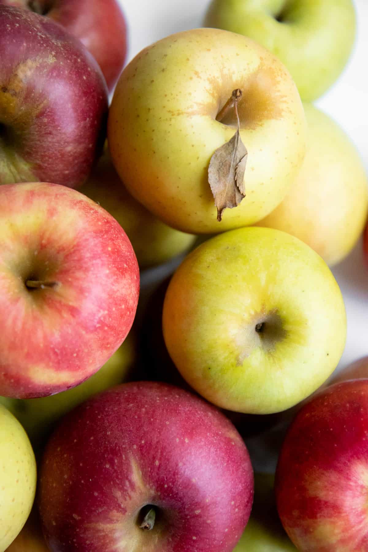 Close-up on a stack of yellow, green, and red apples.