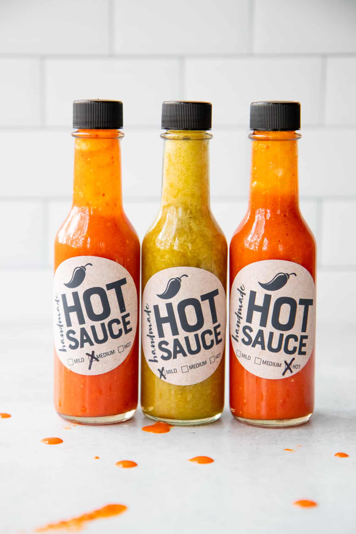 Three bottles of homemade hot sauce, lined up on a counter.