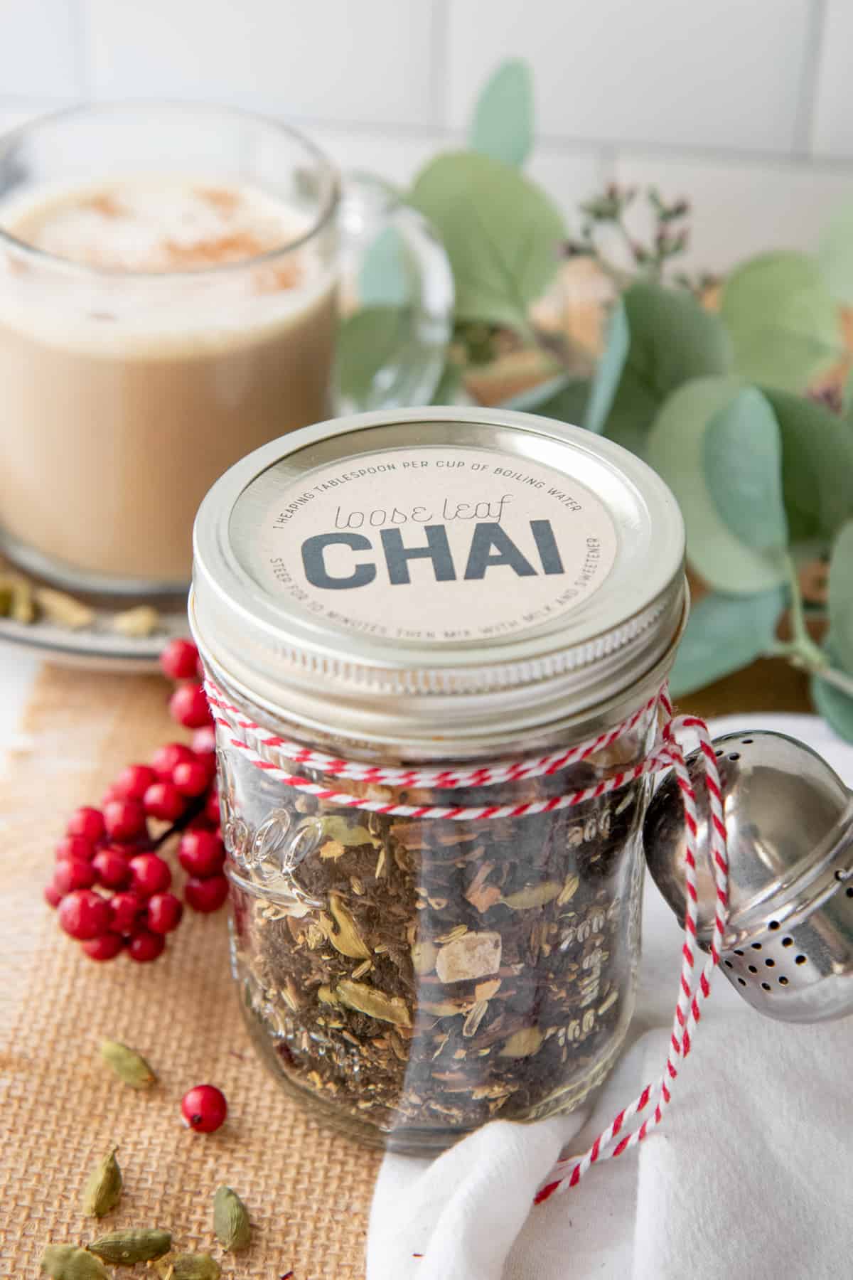 A glass jar filled with loose leaf tea is labeled as "Chai" and tied to a tea ball with baker's twine.