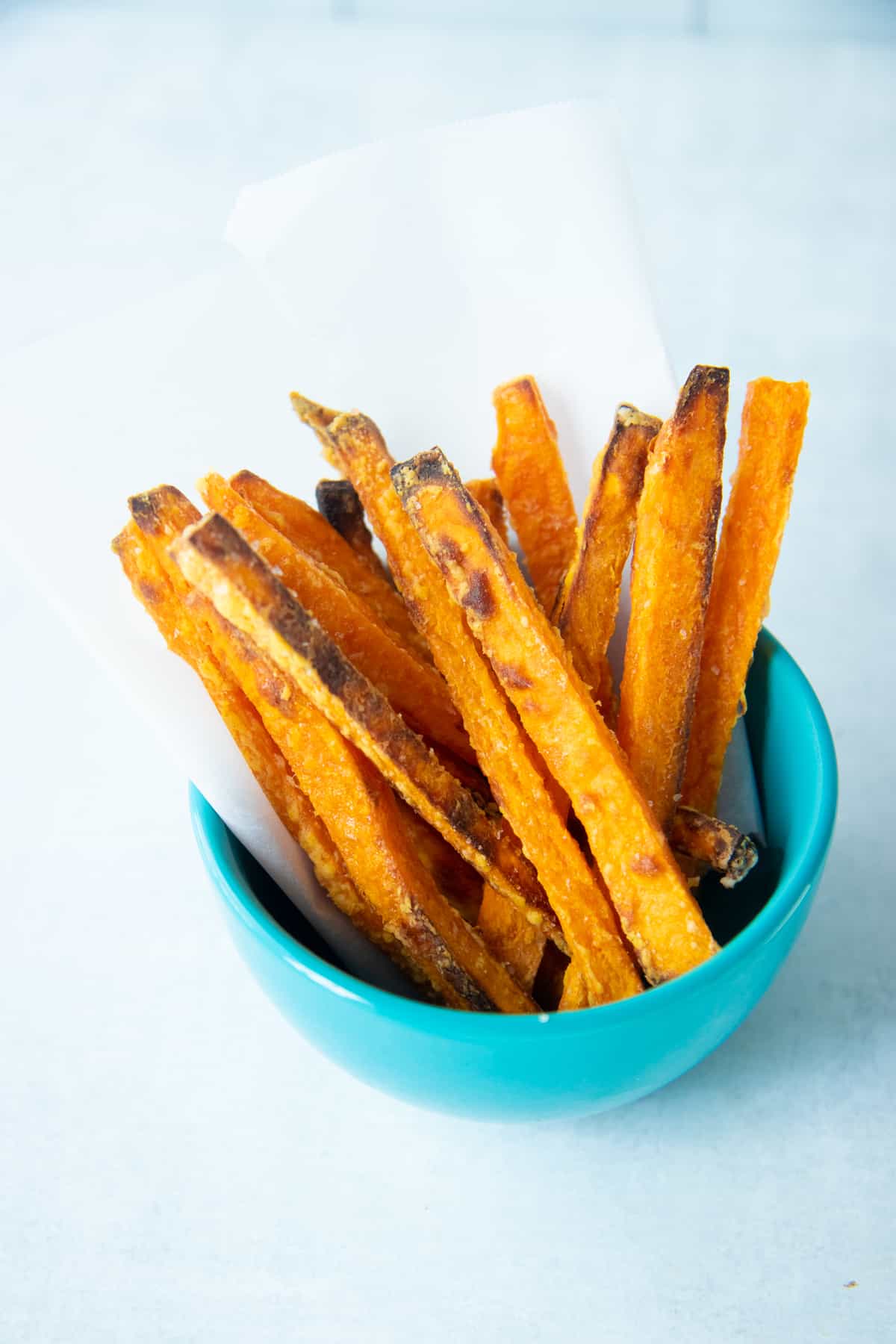 Crispy baked sweet potato fries in a small blue bowl.