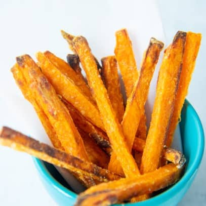 Close up of crispy baked sweet potato fries in a small blue bowl.