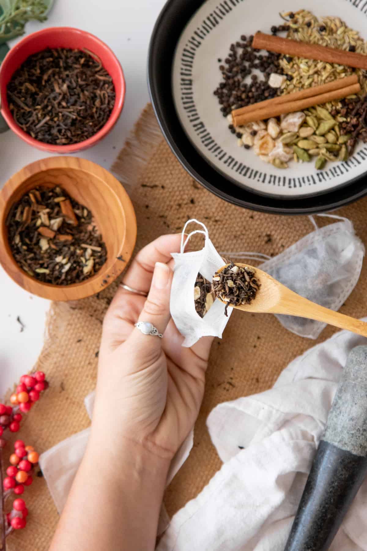 A wooden spoon scoops chai tea mix into fillable tea bags.