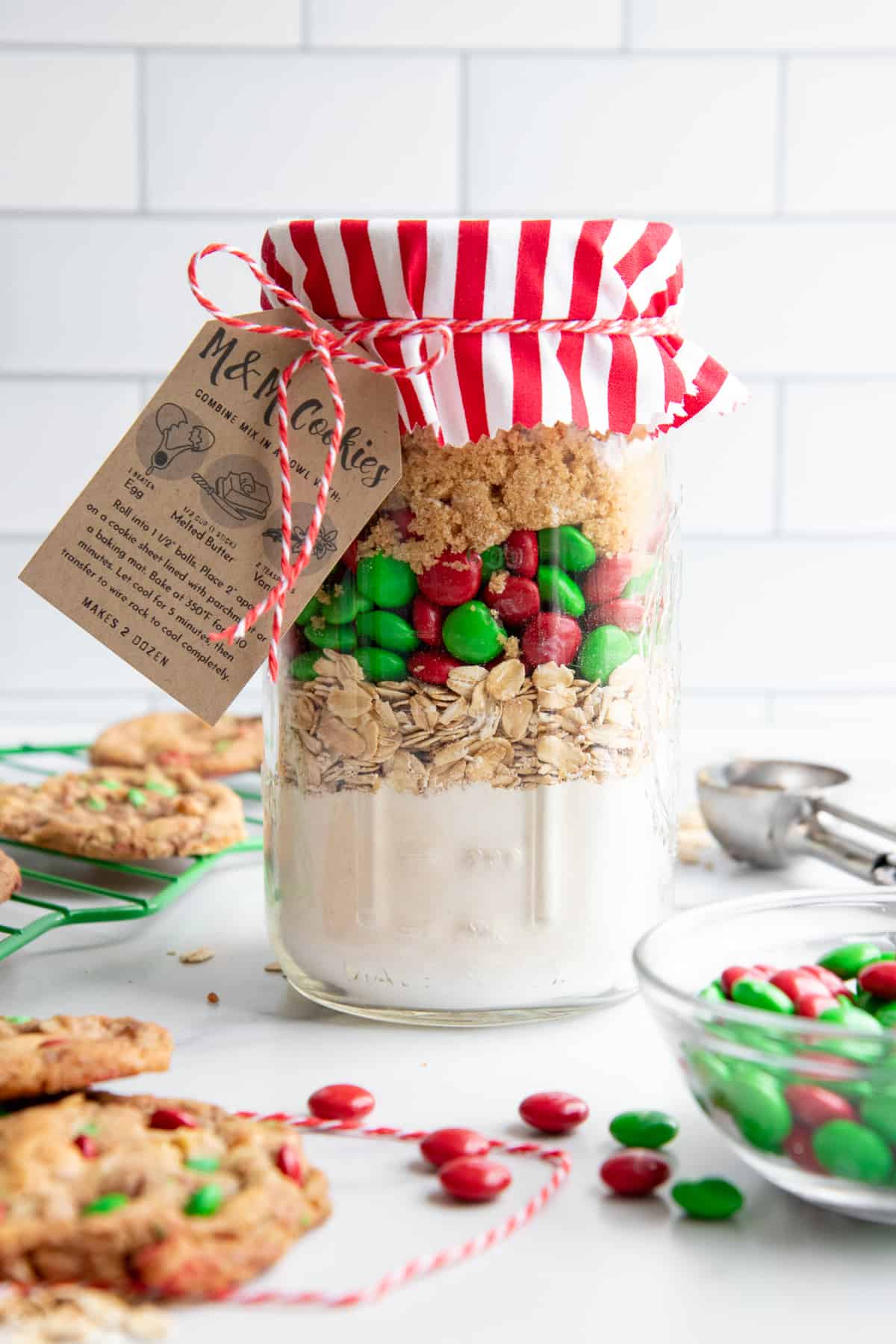 A mason jar filled with even layers of dry ingredients for cookie mix in a jar, topped with fabric, a baking instructions tag, and baker's twine.