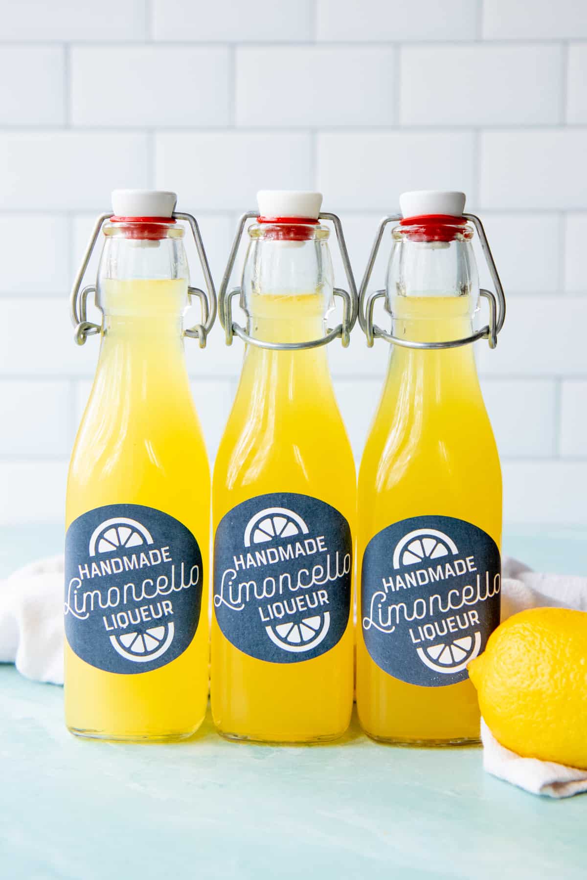 Three bottles of limoncello sitting next to a lemon.