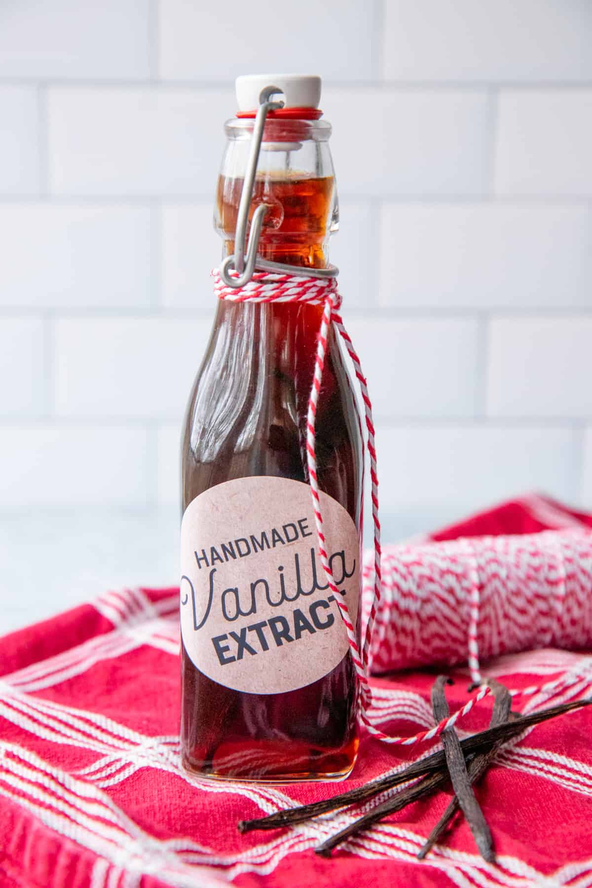A bottle of homemade vanilla extract is labeled and wrapped in baker's twine.