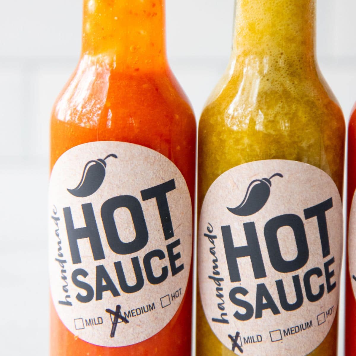 Two finished hot sauces (one red and one green) in bottles with labels