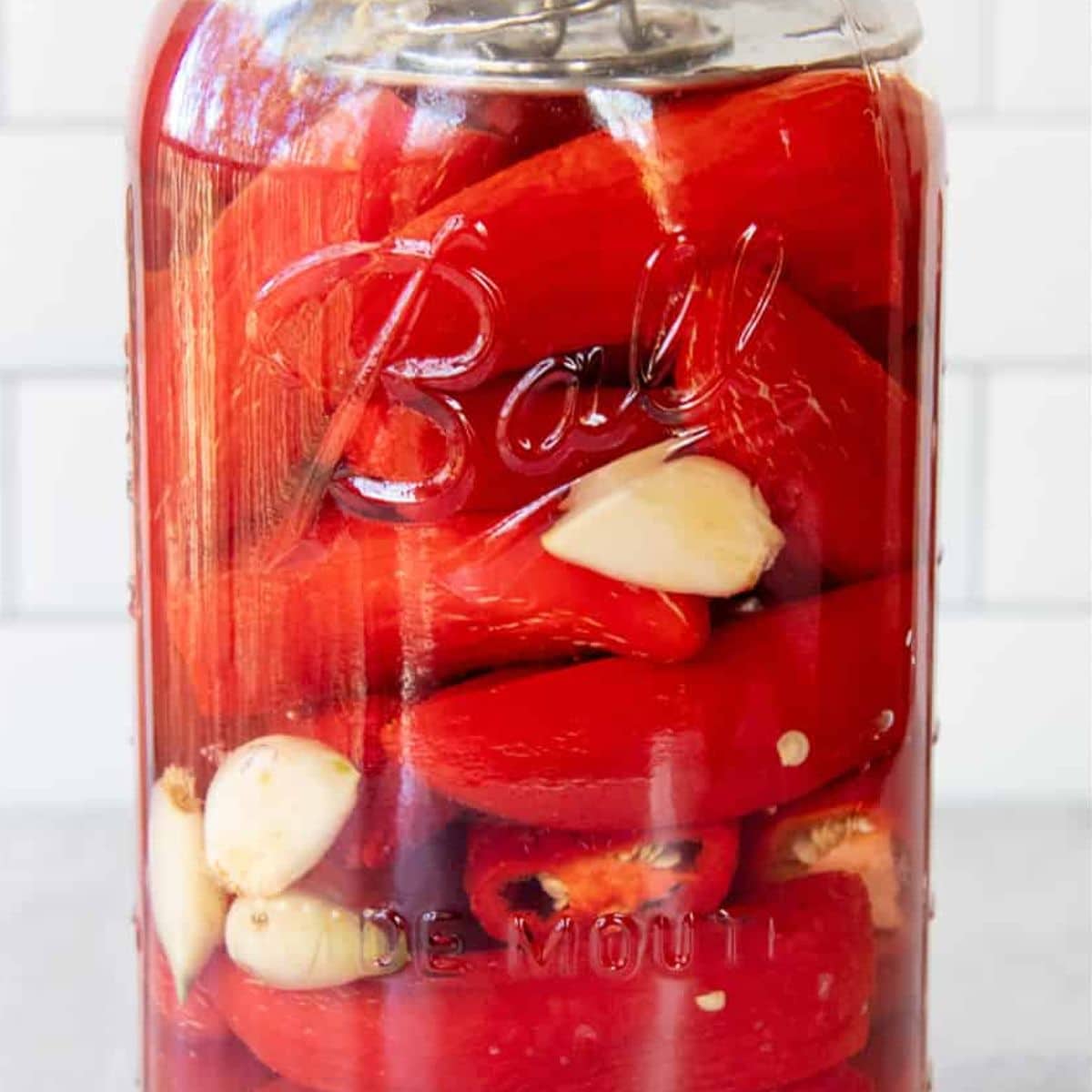 Peppers and garlic ferment in a clear glass jar