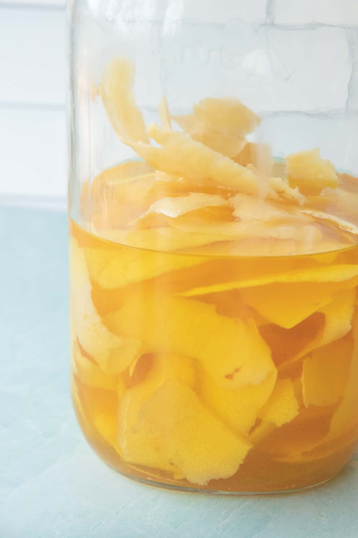 Lemon peels infusing into grain alcohol in a glass mason jar.