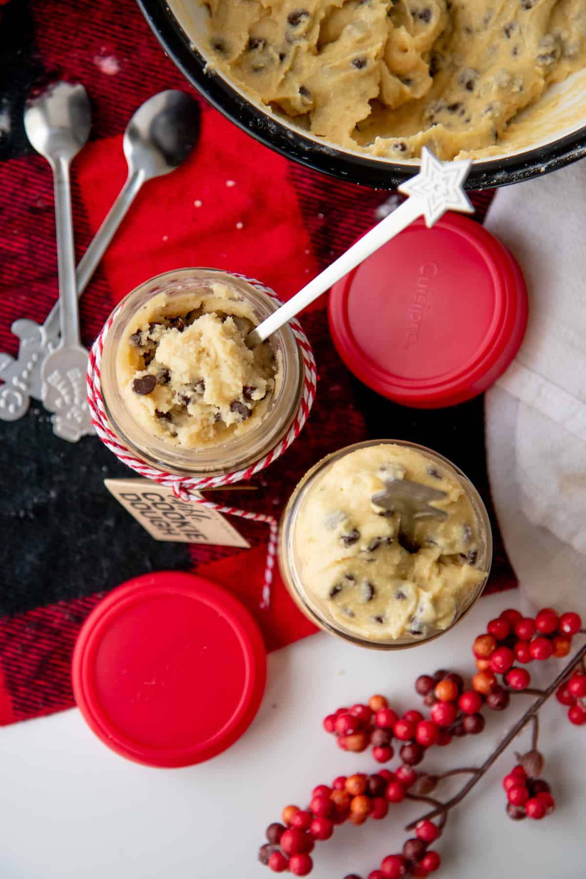 Overhead shot of two jars of eggless cookie dough on a red and black plaid background.