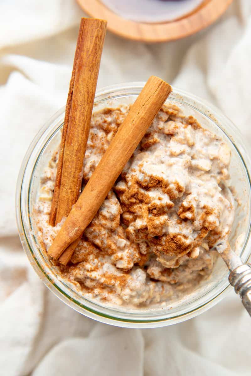 Two cinnamon sticks sit on top of a jar of chai overnight oats.