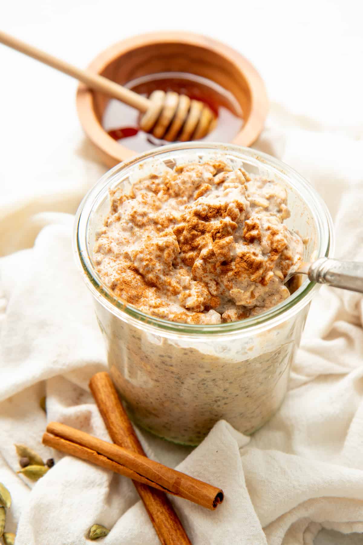 A spoon rests in a glass jar of chai latte overnight oats.