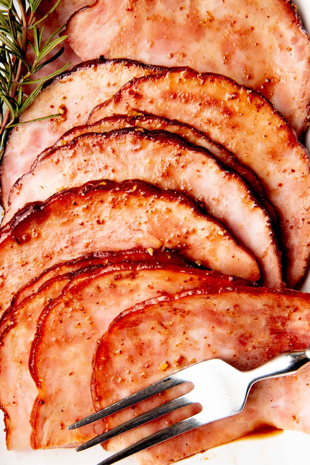 Ham is thinly sliced. A silver fork sits in the bottom right corner.
