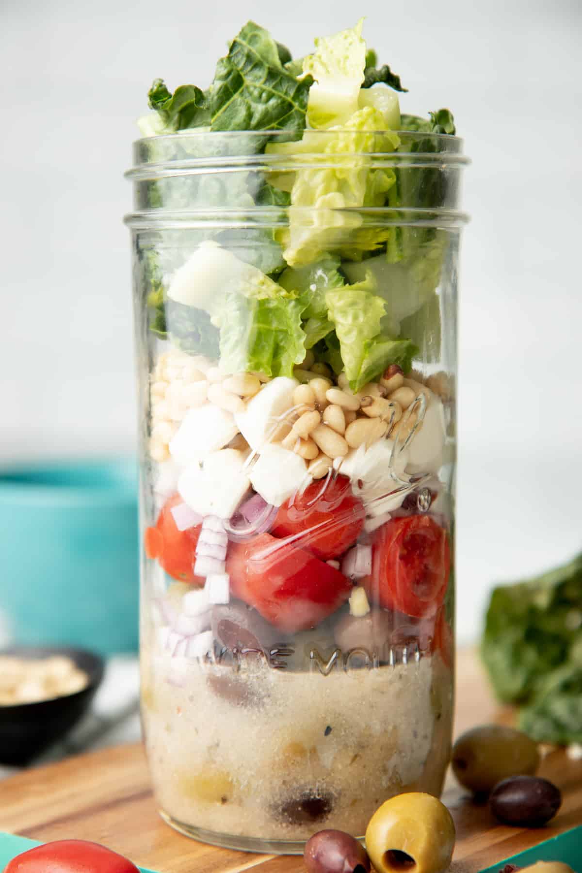Components of an Italian chopped salad are layered in a glass mason jar.