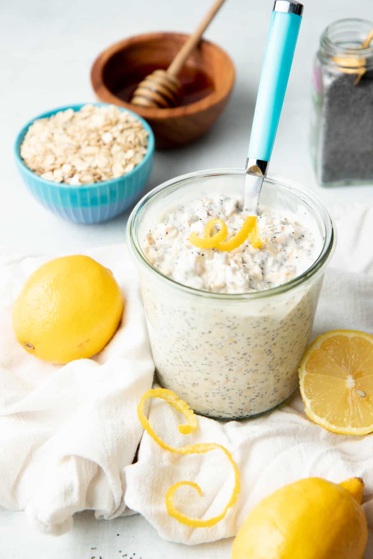 A jar is filled with lemon poppyseed overnight oats. It is topped with a twirl of lemon zest.