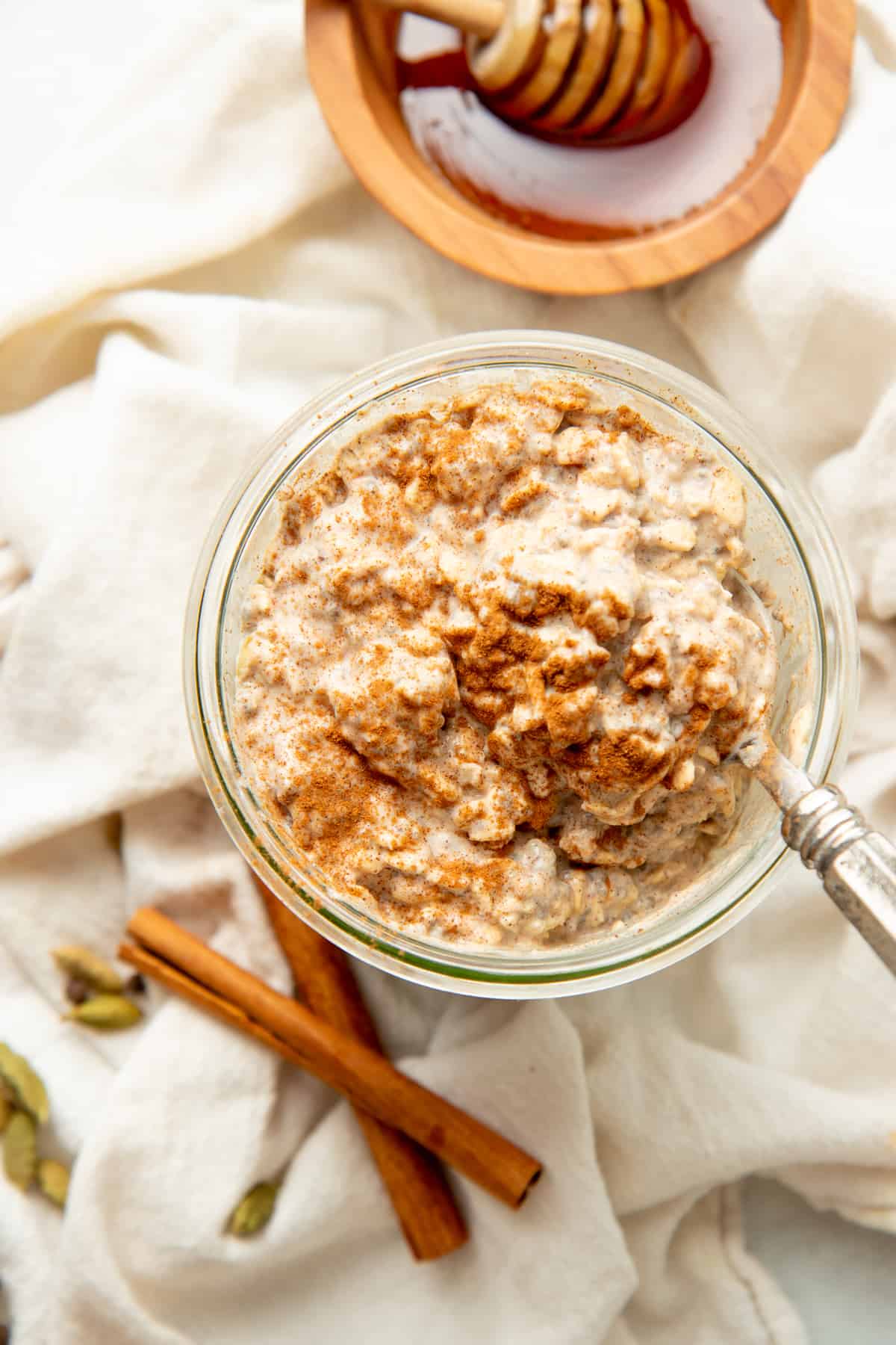 A spoon rests in a glass jar of chai latte overnight oatmeal.