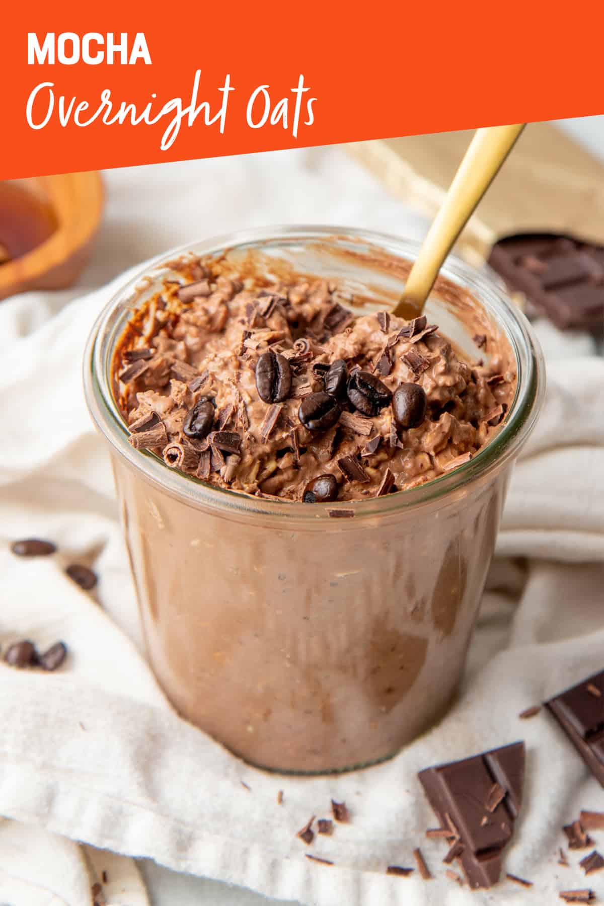 A gold spoon sits in a jar full of mocha overnight oats. A text overlay reads "Mocha Overnight Oats."