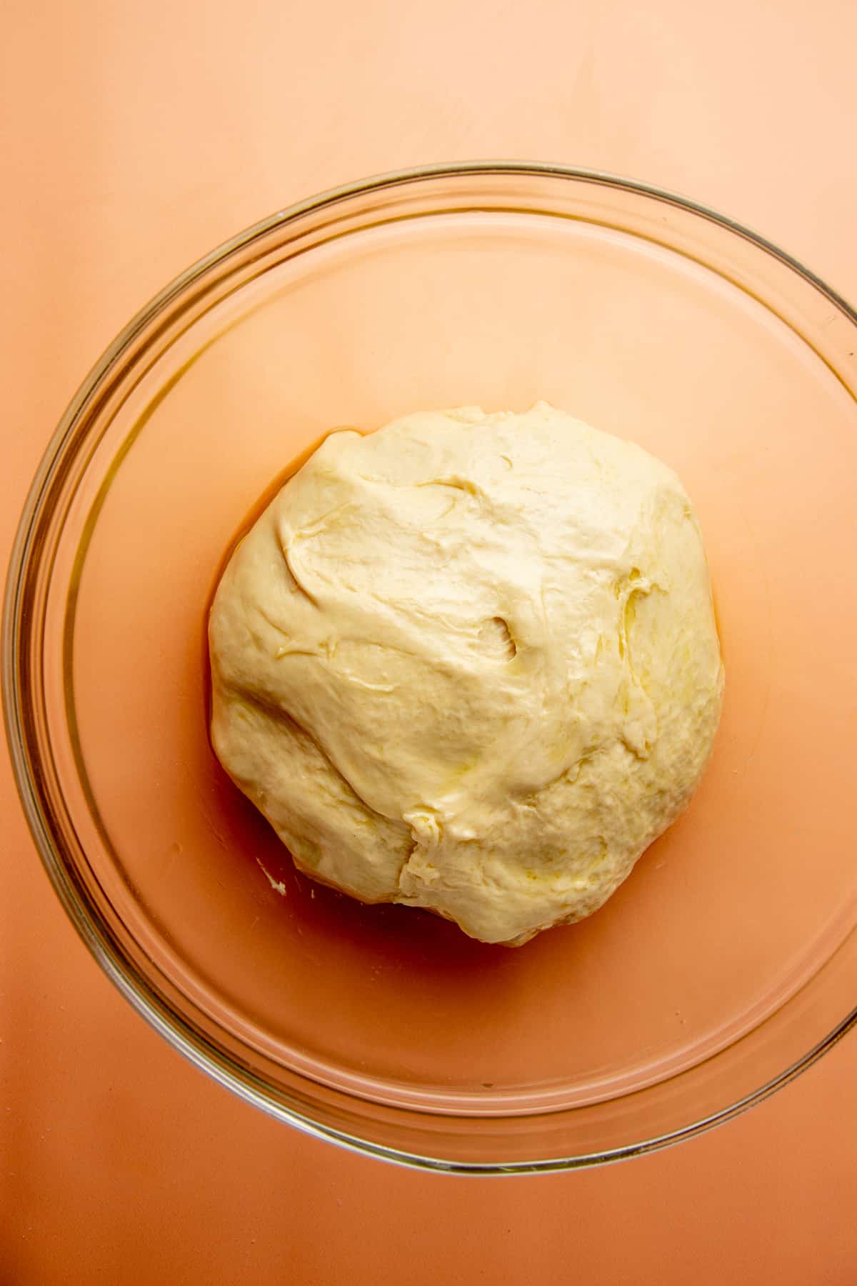 Unrisen dough sits in a glass bowl.