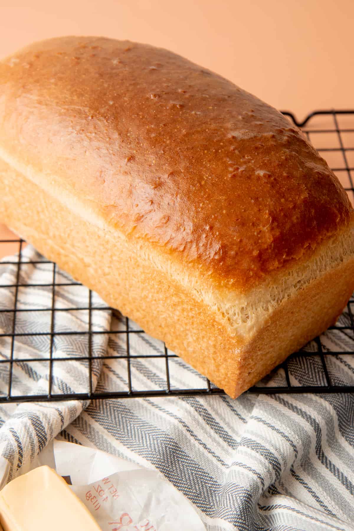 A baked loaf of bread sits on a wire rack.