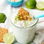 A small glass jar is filled with overnight oats and topped with graham cracker and lime twists.