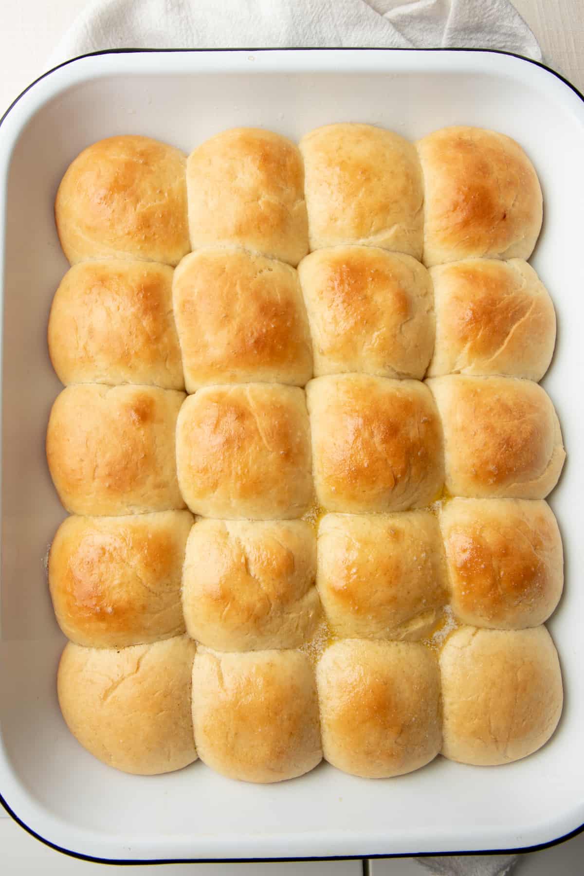 A pan of buttery yeast rolls sits on a cloth napkin.