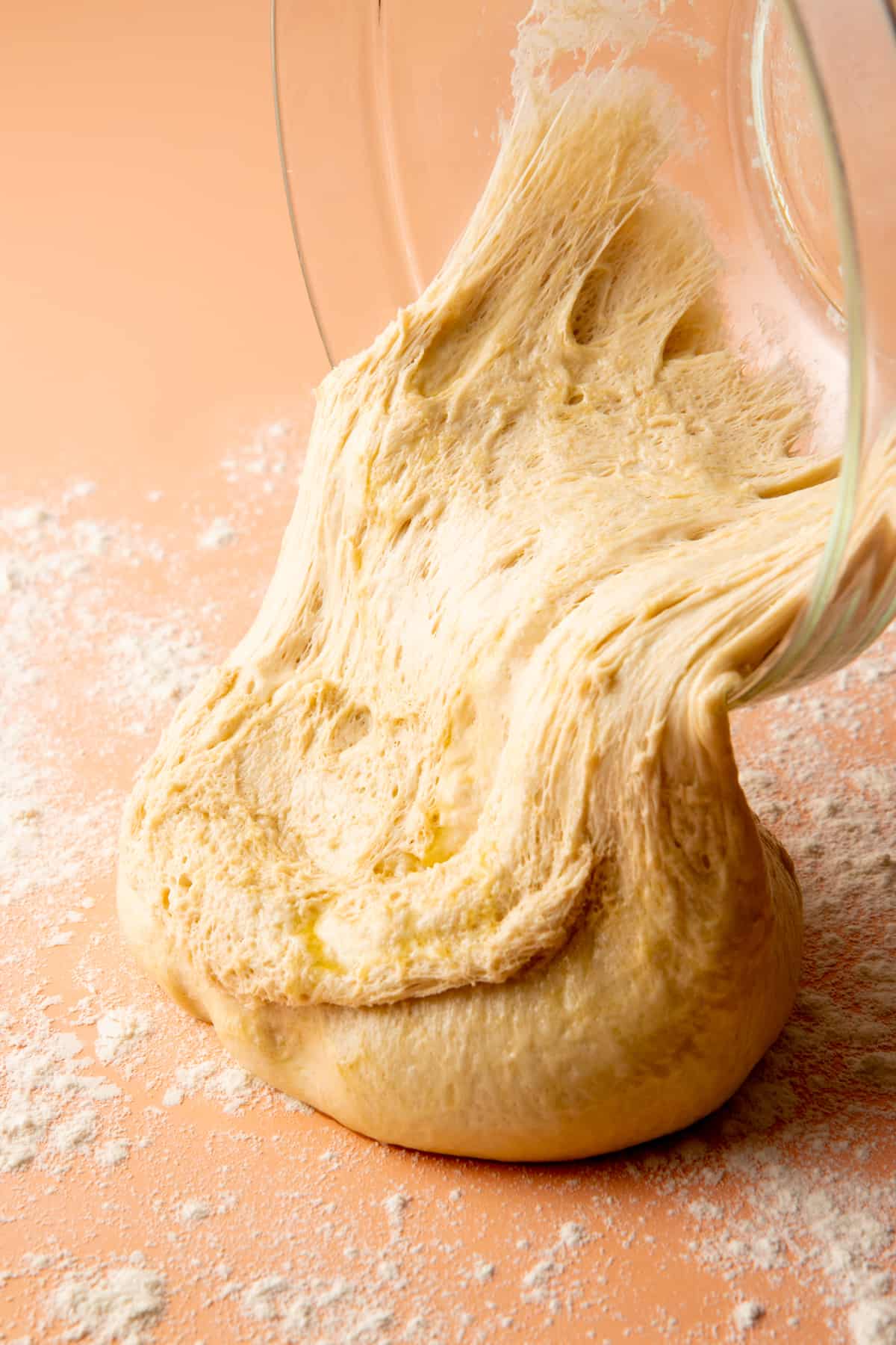 A bowl of risen dough pours out onto a floured cutting board.