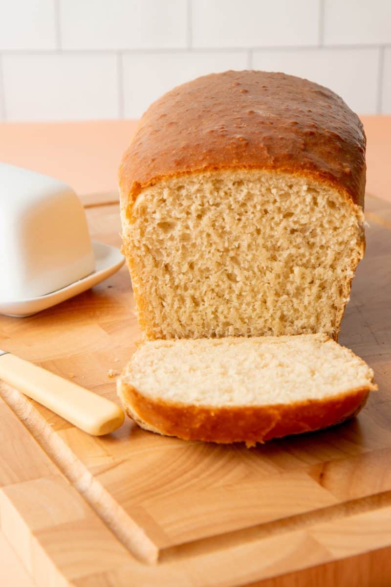 A sliced loaf of bread sits on a wooden cutting board.