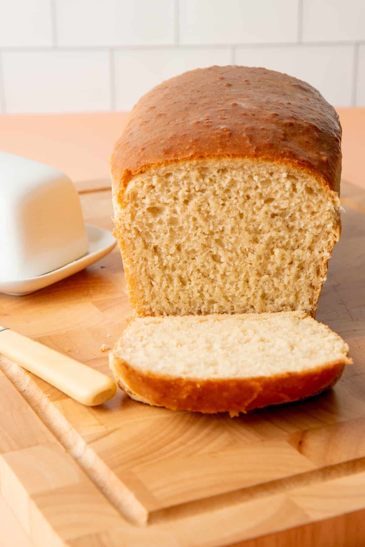 A sliced loaf of bread sits on a wooden cutting board.