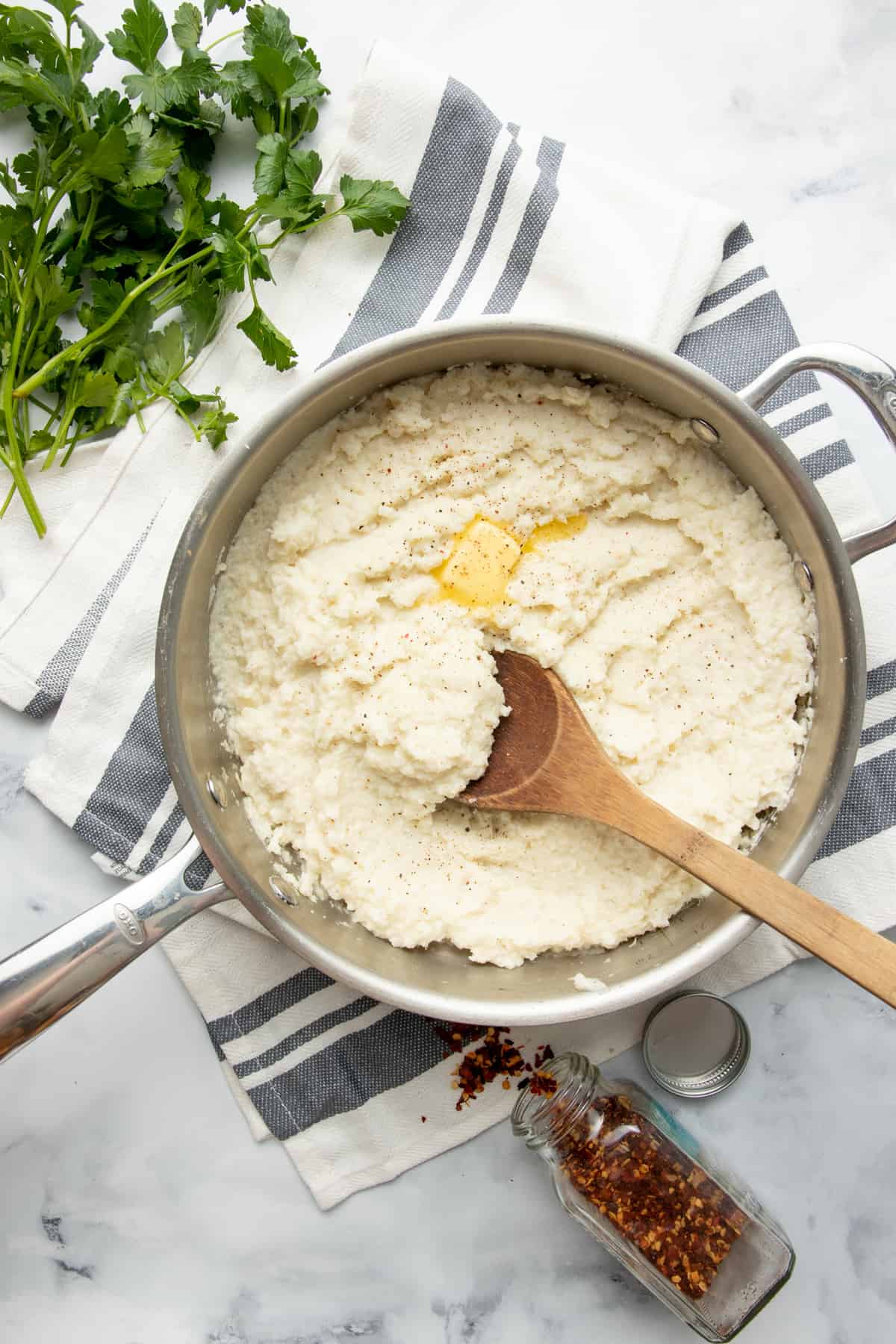 Cauliflower grits in a saucepan are mixed with a wooden spoon.
