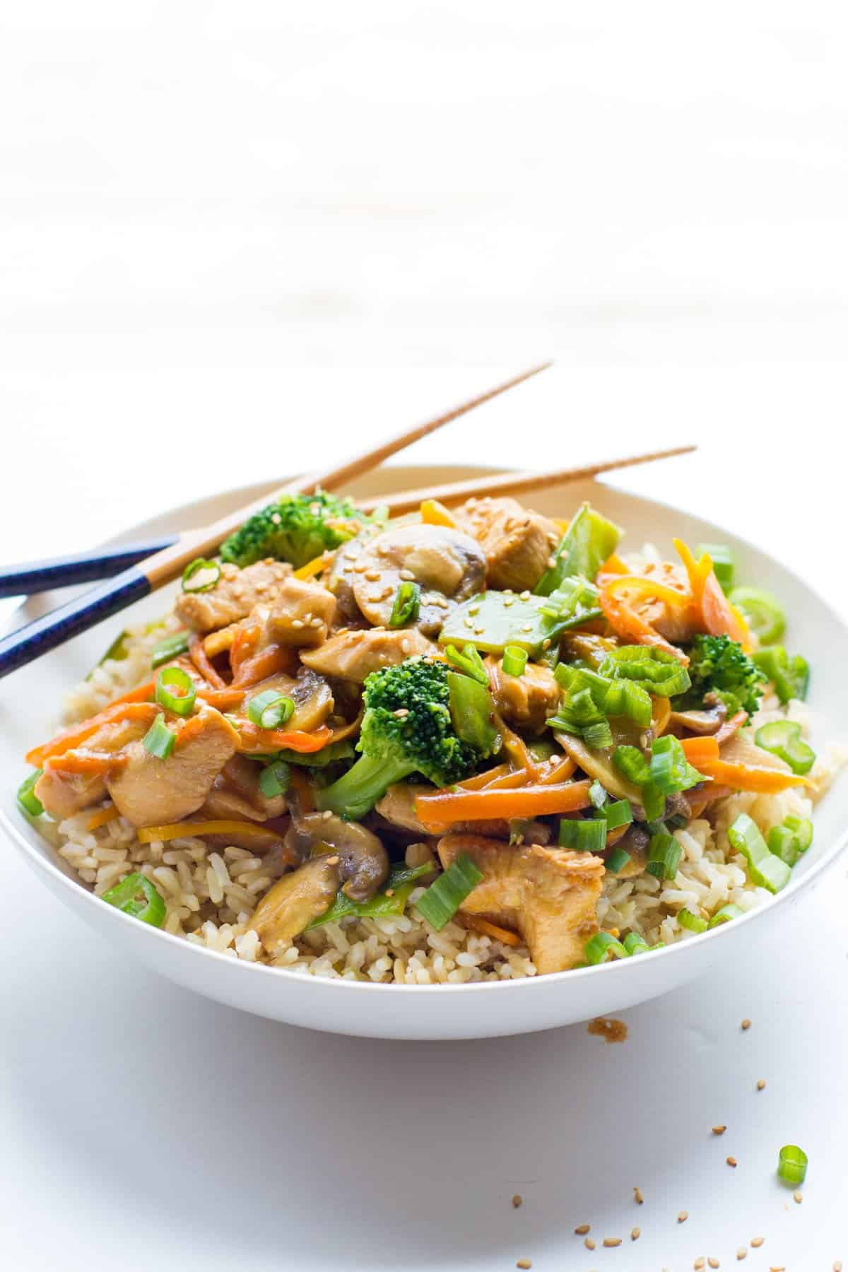 Healthy Chicken Stir Fry sits in a bowl with chopsticks.