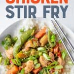 Stir fry sits in a bowl with chopsticks. A text overlay reads, "Healthy Chicken Stir Fry".