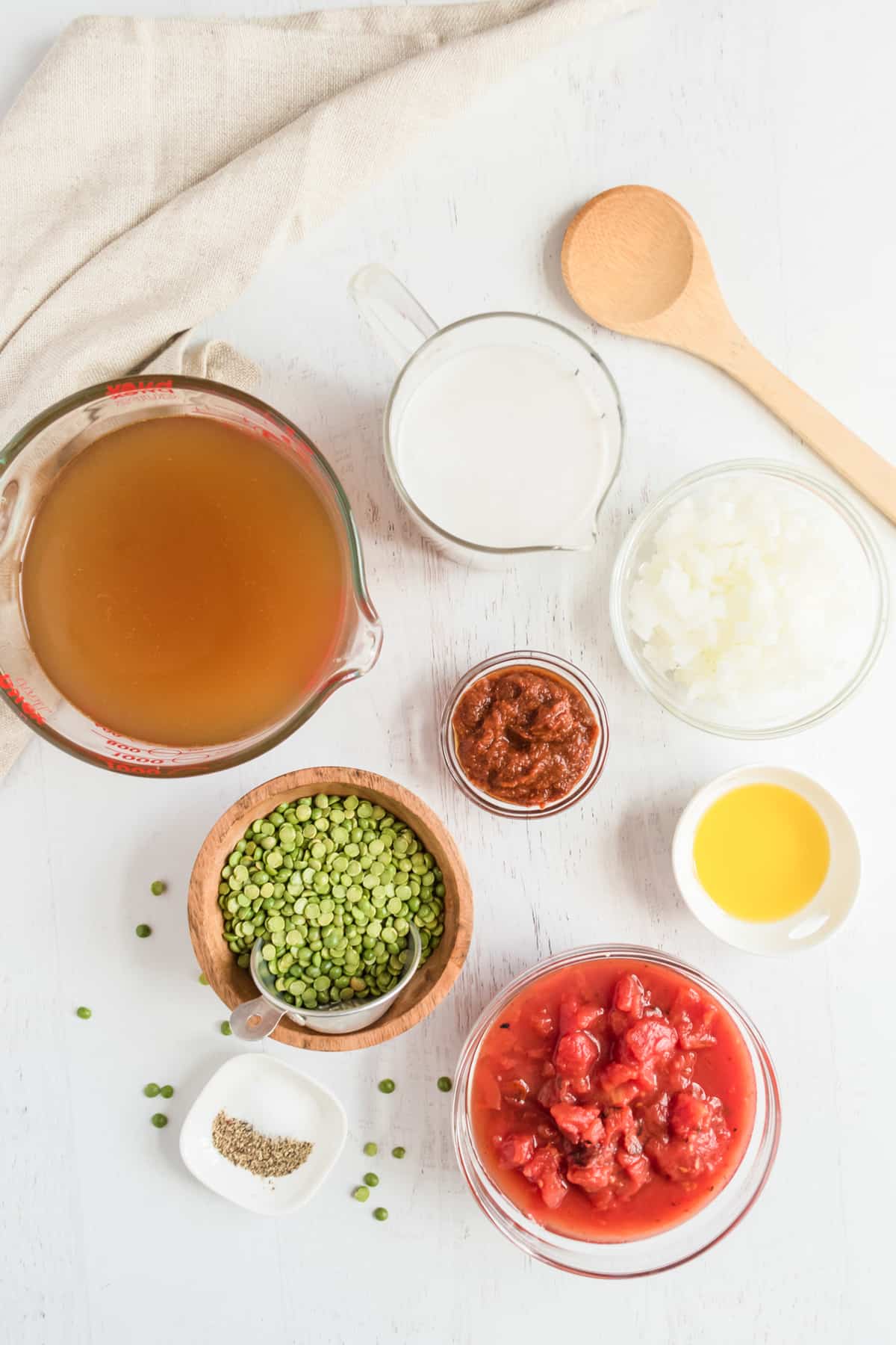 Ingredients to make curry sit together - vegetable broth, coconut milk, tomatoes, red curry paste, split peas, butter, and onion.