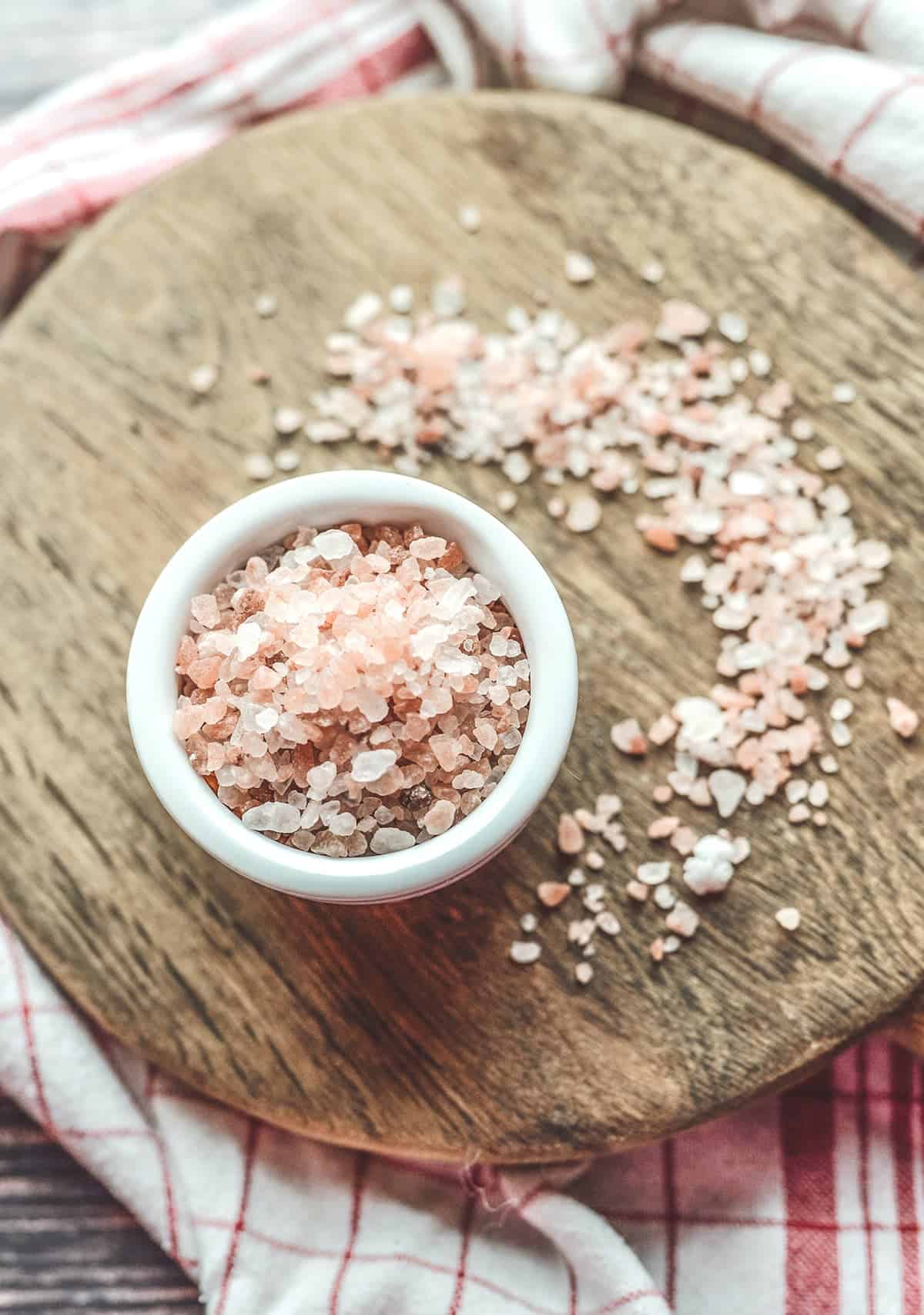 Pink sea salt for a grounding technique for anxiety sits in a bowl on a wooden board.