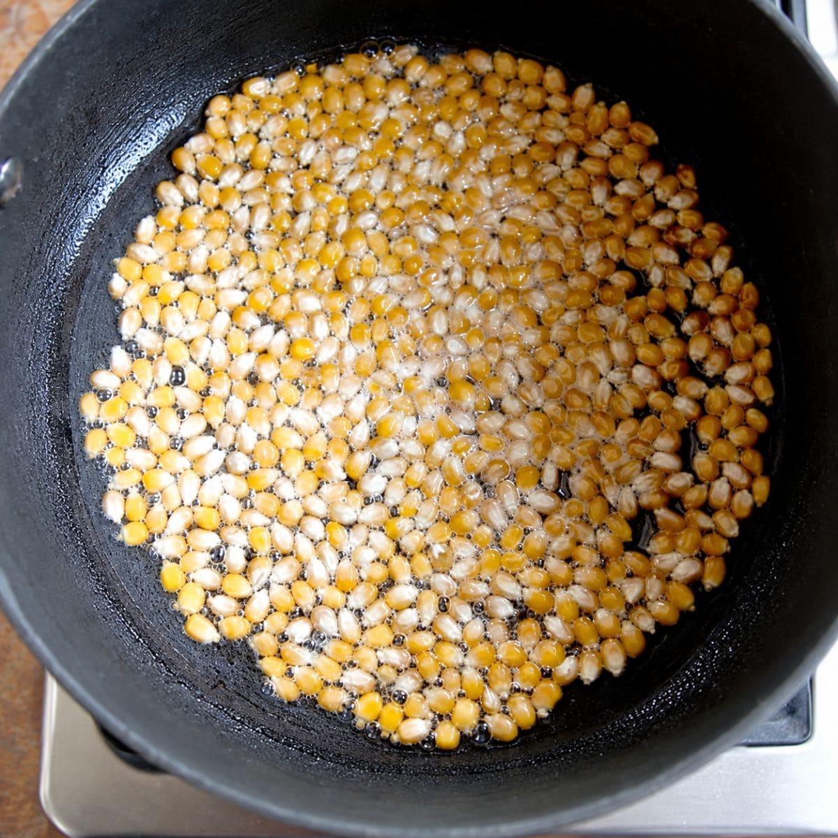 Popcorn kernels cooking in coconut oil in pot