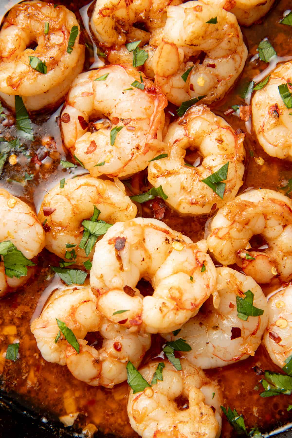 Cooked shrimp sit in sauce.