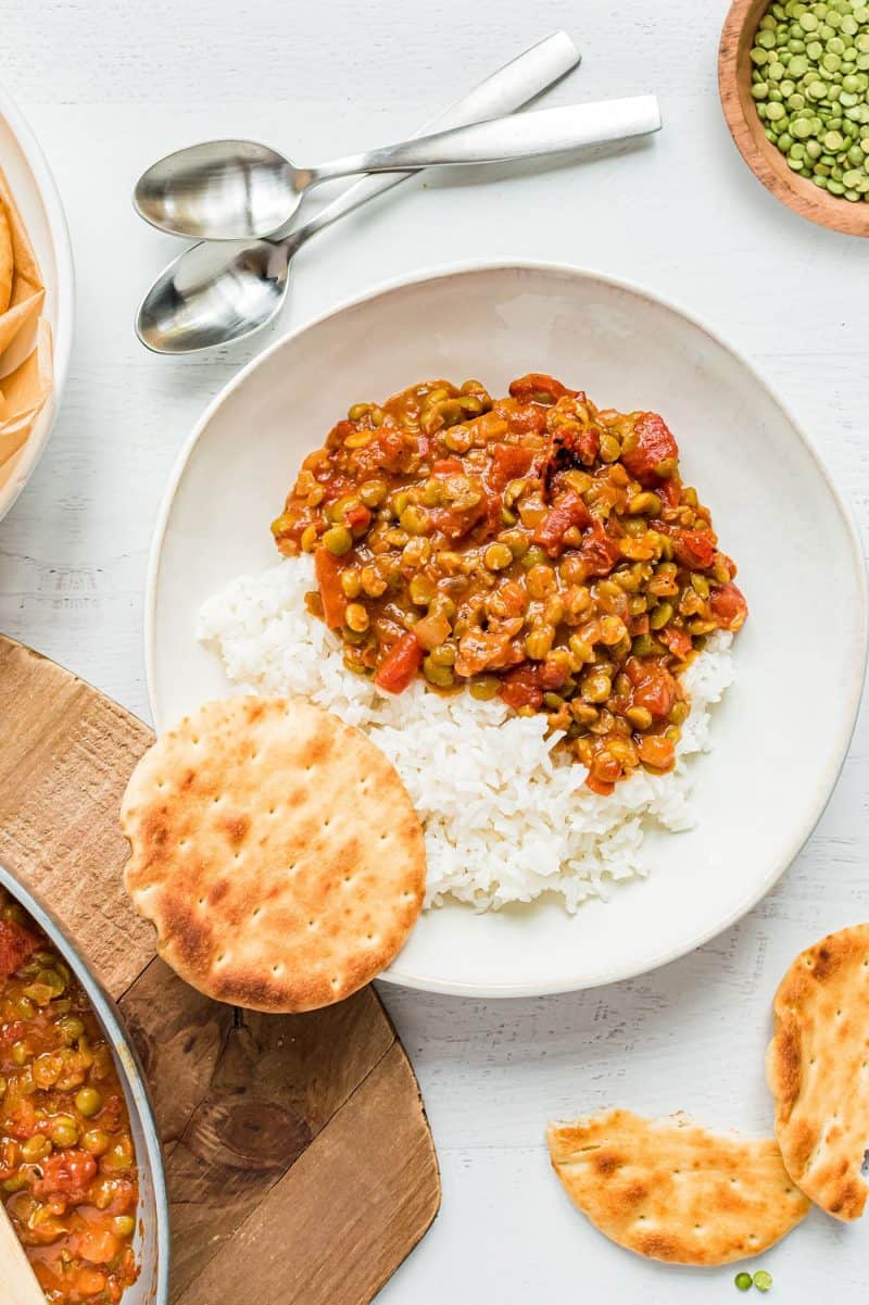 Split Pea Curry sits in a bowl over rice. Naan bread sits nearby.