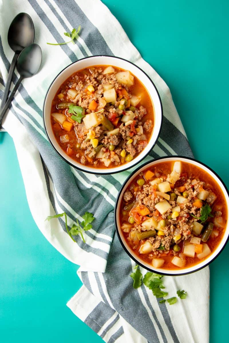 Two bowls of vegetable beef soup sit on a cloth napkin.