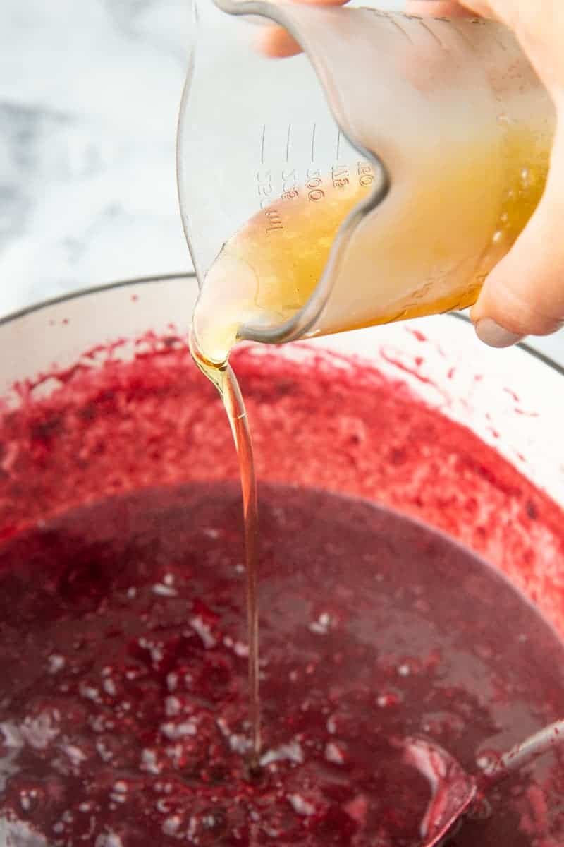 Pouring agave into boiling mixed berry puree.
