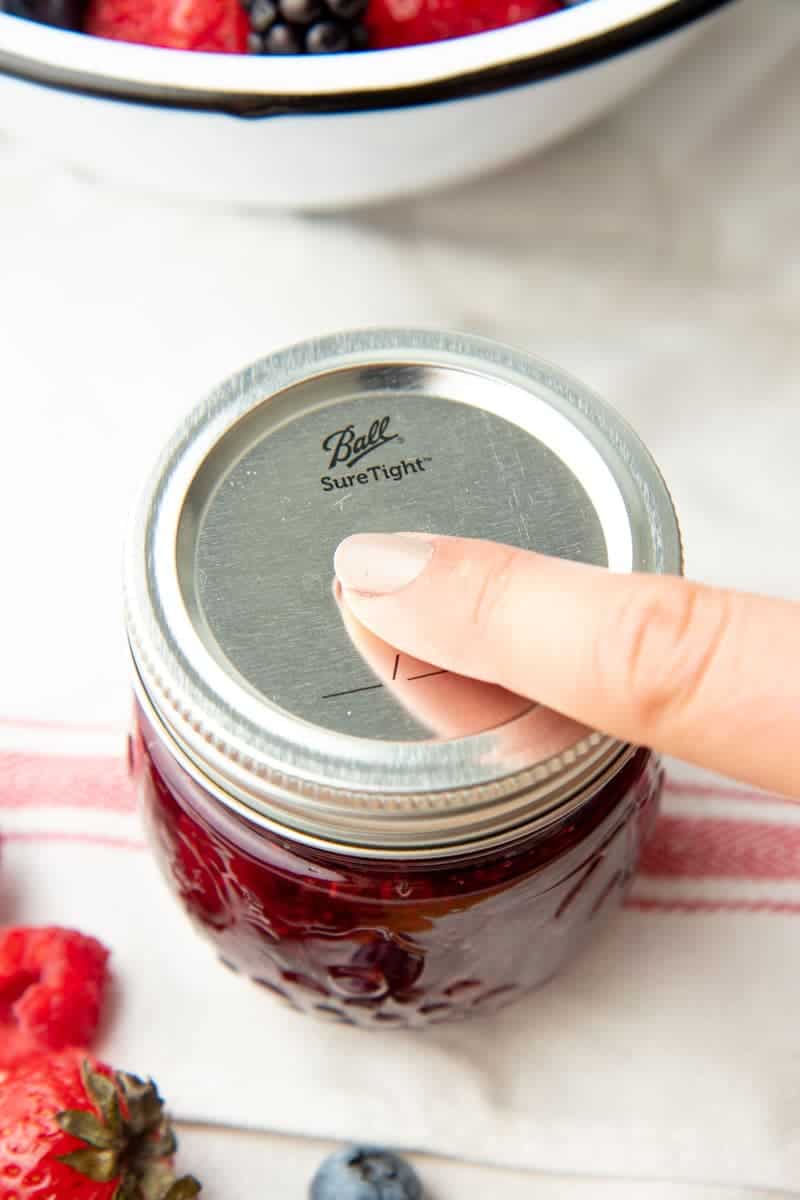 Close-up of finger checking the Ball Sure Tight lid for proper seal.