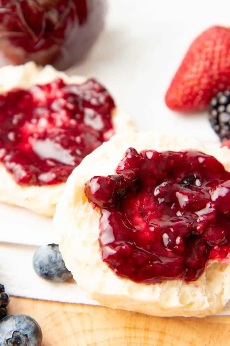 Close-up of finished mixed berry jam spread onto a split biscuit.