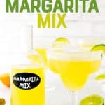 Bottle of homemade margarita mix next to margarita with a salt rim and fresh citrus. A text overlay reads, "DIY Margarita Mix."