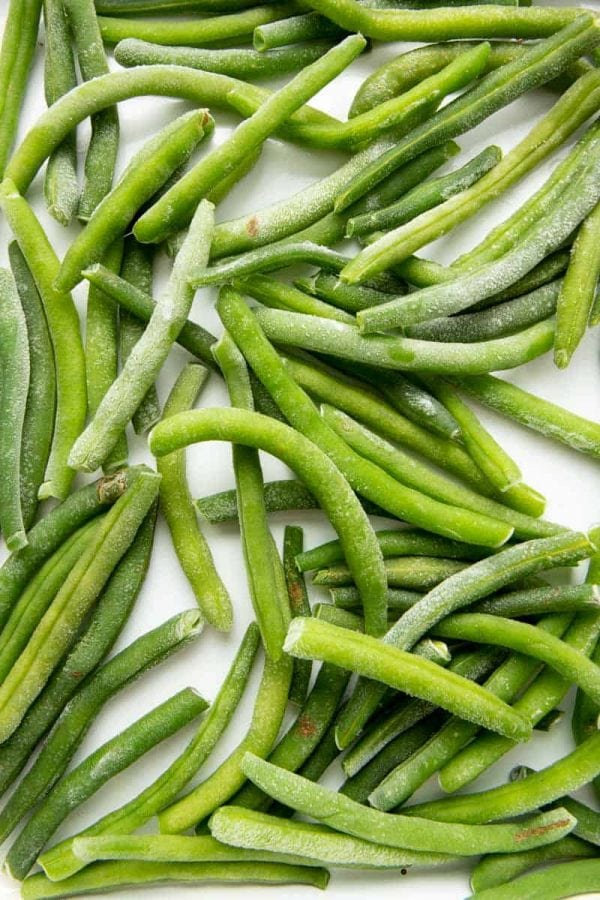 Overhead of individually frozen green beans on a baking sheet.