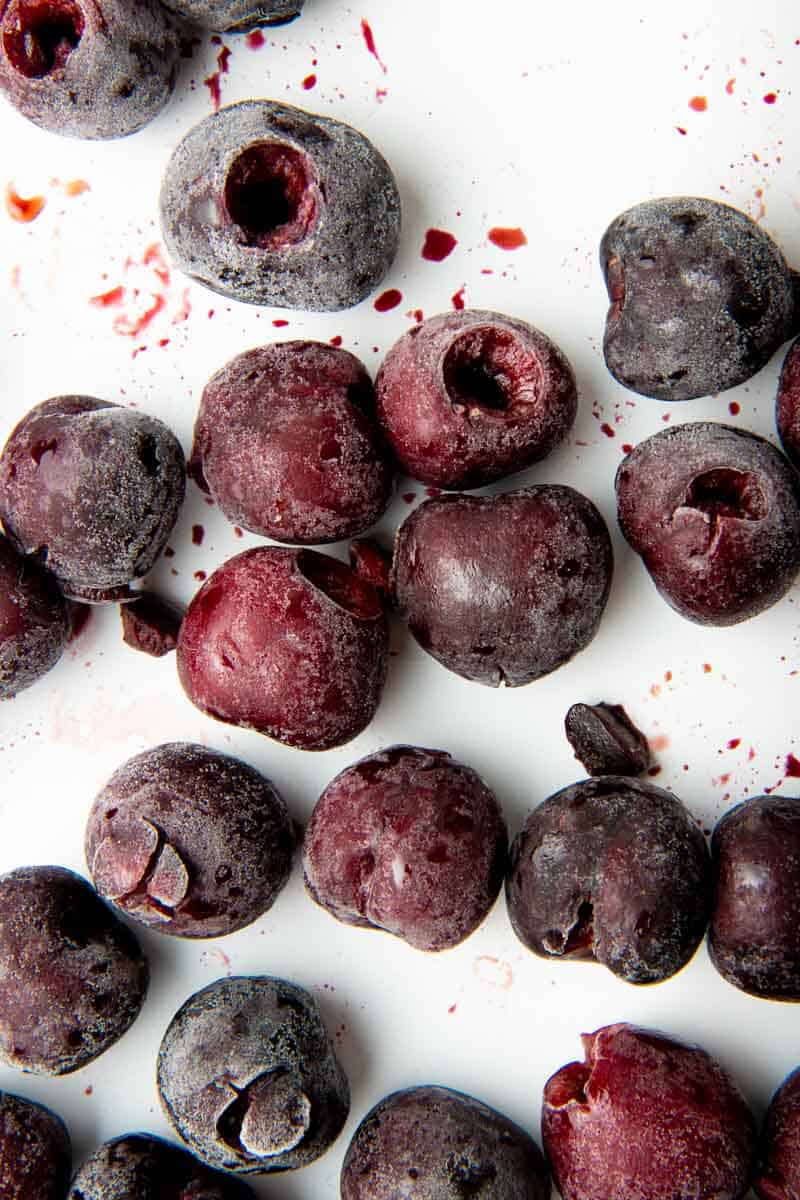 Close up of frozen, pitted cherries on a baking sheet.